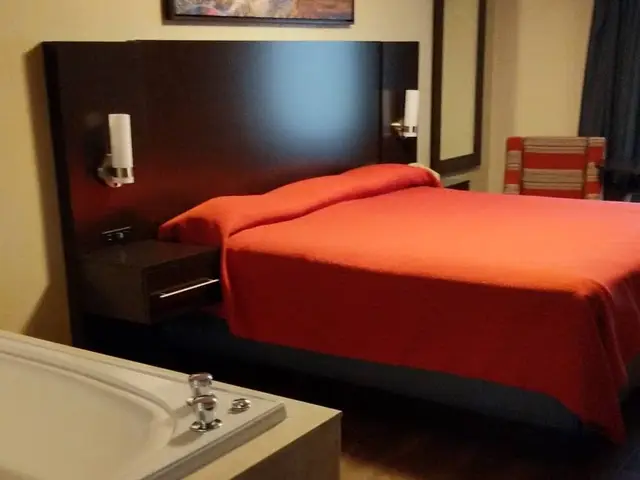 Wide view of the jacuzzi tub and king bed with red bedspread