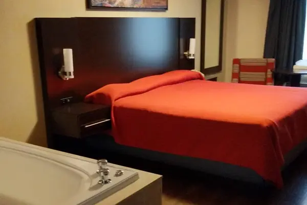 Wide view of the jacuzzi tub and king bed with red bedspread