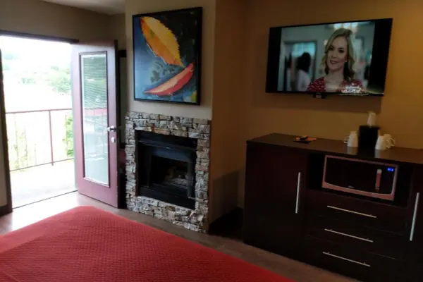 Stone fireplace beside the open balcony door with microwave and dresser