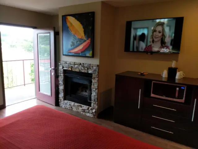 Stone fireplace beside the open balcony door with microwave and dresser